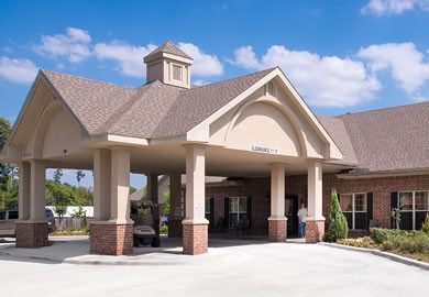 A modern building entrance with columns and a peaked roof against a blue sky.
