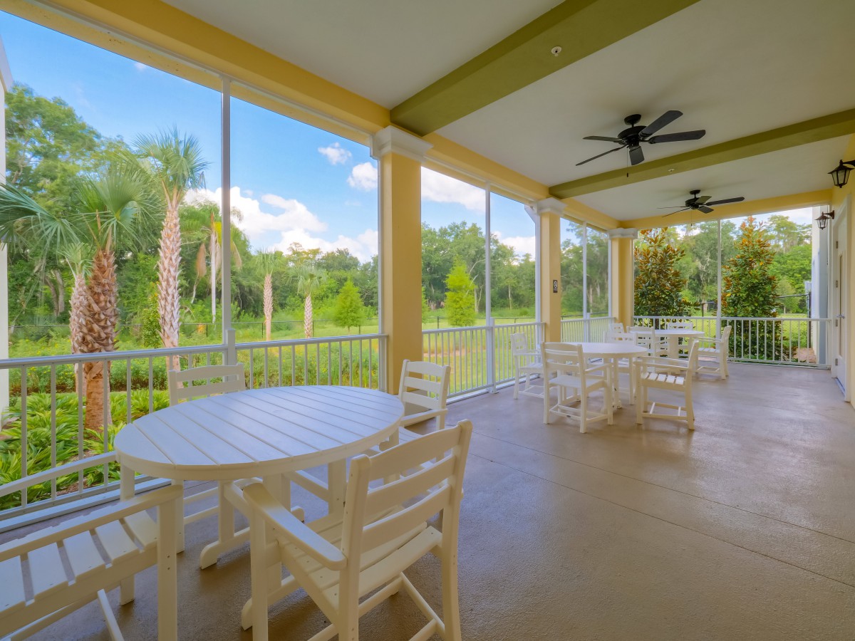 A serene outdoor seating area on a covered patio overlooking lush greenery.