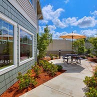 A modern patio area with outdoor furniture and umbrella in a landscaped backyard.