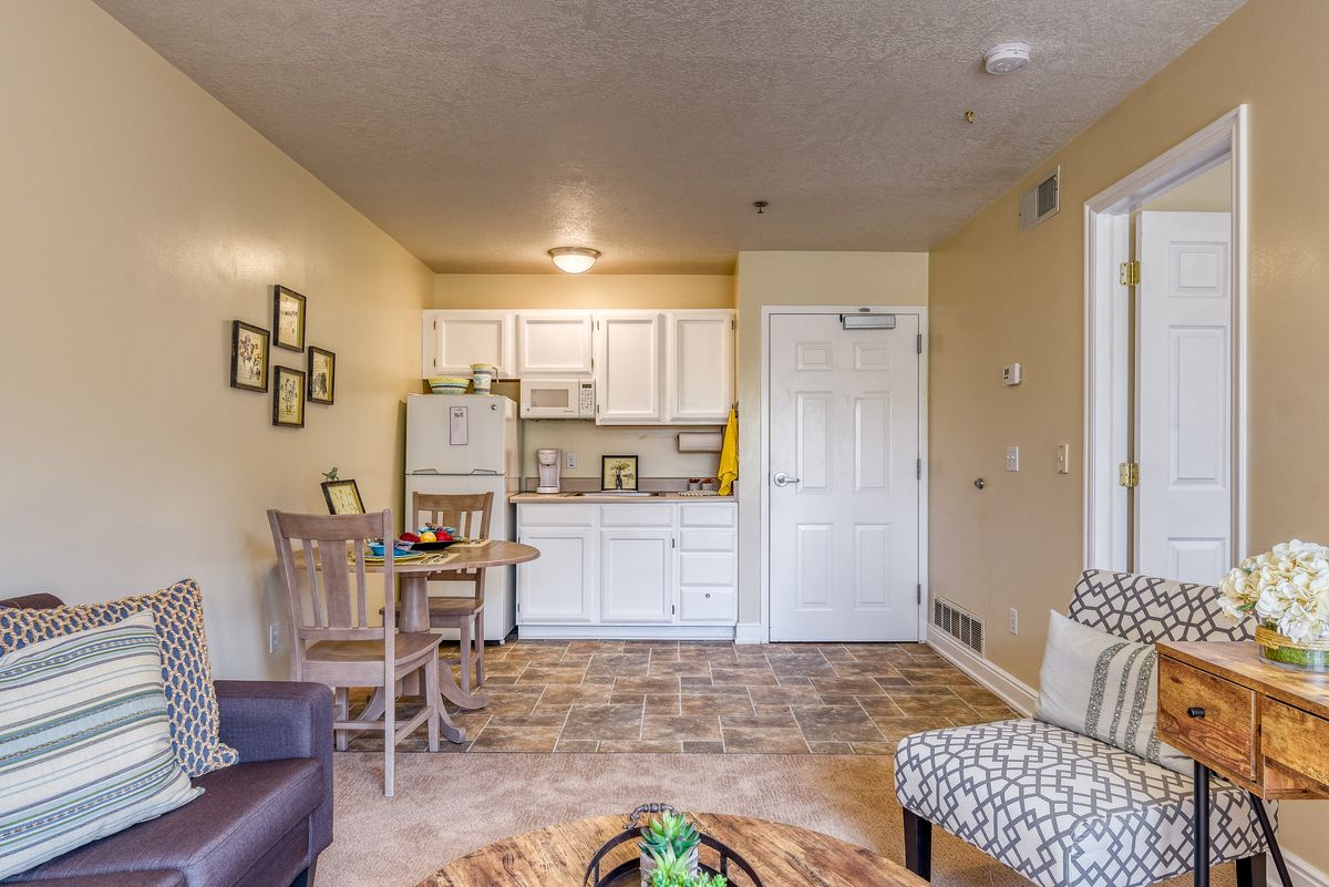 A cozy apartment interior featuring a small kitchenette and dining area, complemented by comfortable seating and modern decor.