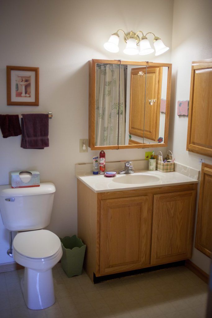 A well-organized bathroom featuring a sink with a mirror, toilet, and wooden cabinets.