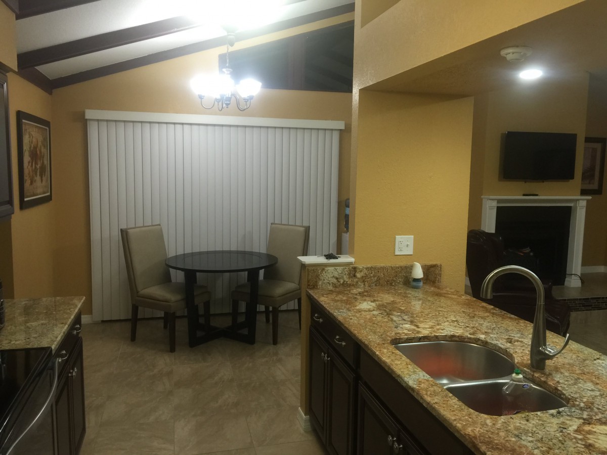 A cozy kitchen and dining area featuring granite countertops and a small round table with chairs.