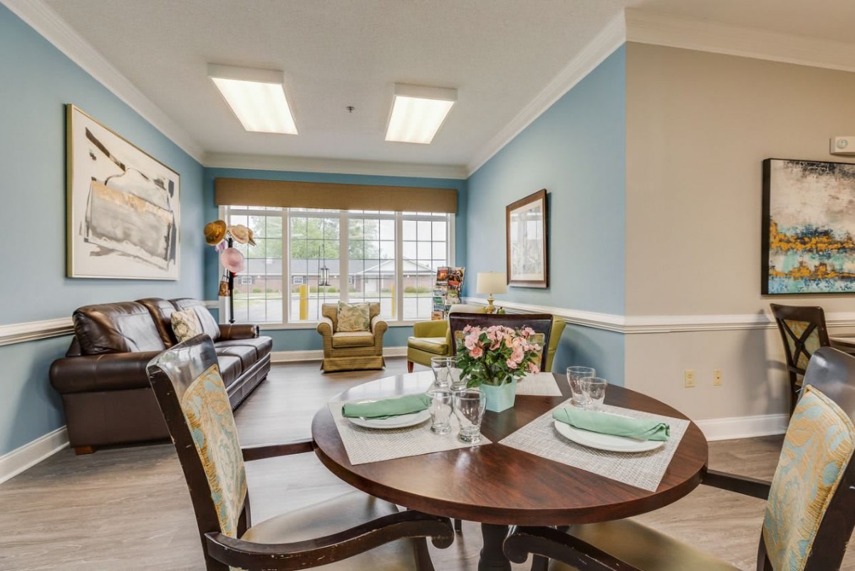 A cozy living and dining area with blue walls, modern furniture, and a large window.