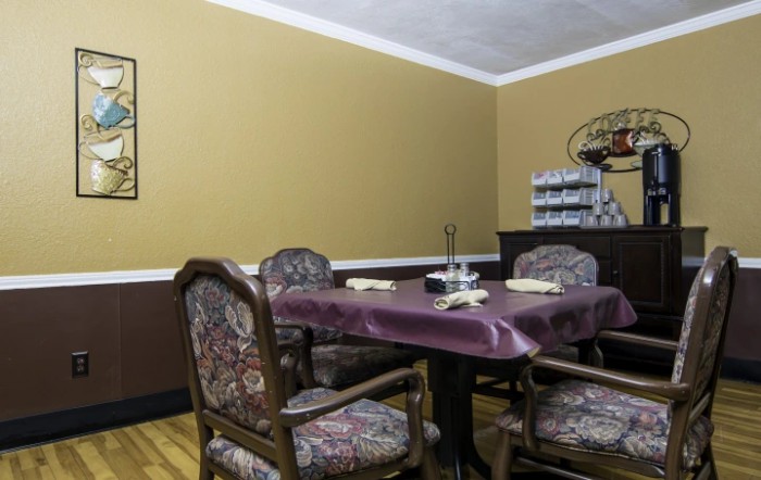 A traditional dining room with a table and chairs, featuring warm-toned walls and decorative elements.