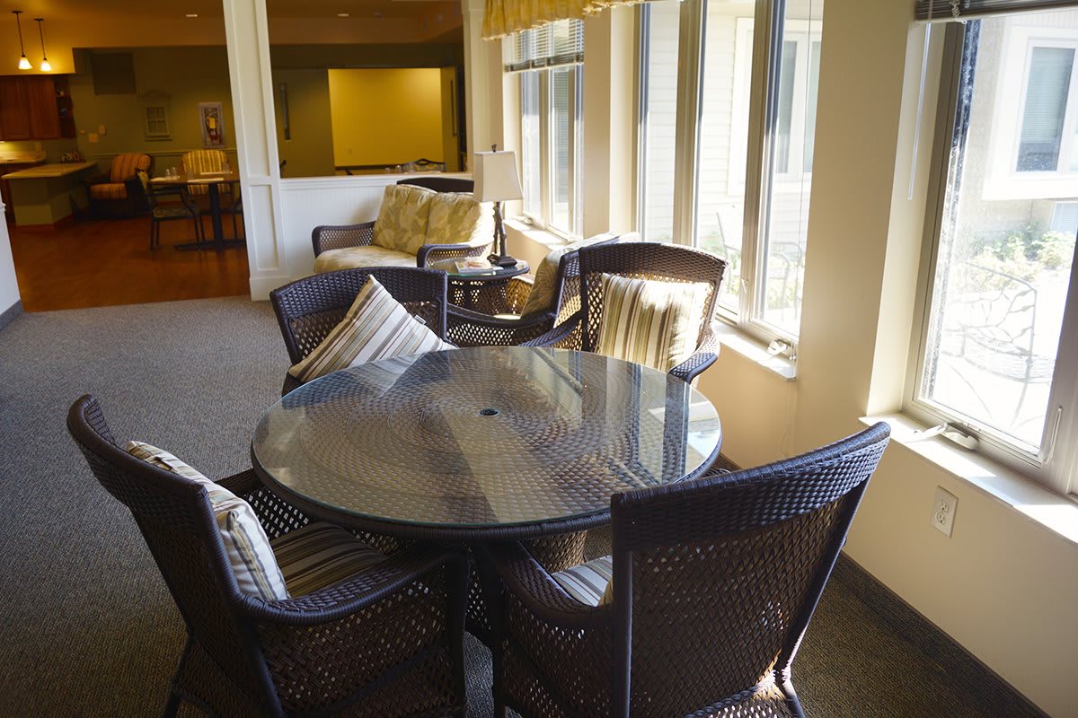A cozy indoor dining area with a round table and wicker chairs, bathed in natural light from nearby windows.