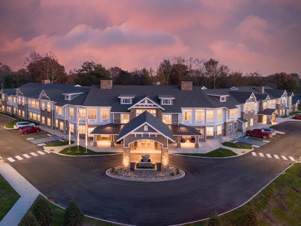 A beautifully lit hotel at sunset with a circular driveway in front.