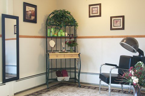 A cozy waiting room corner with a decorative shelf and chair.