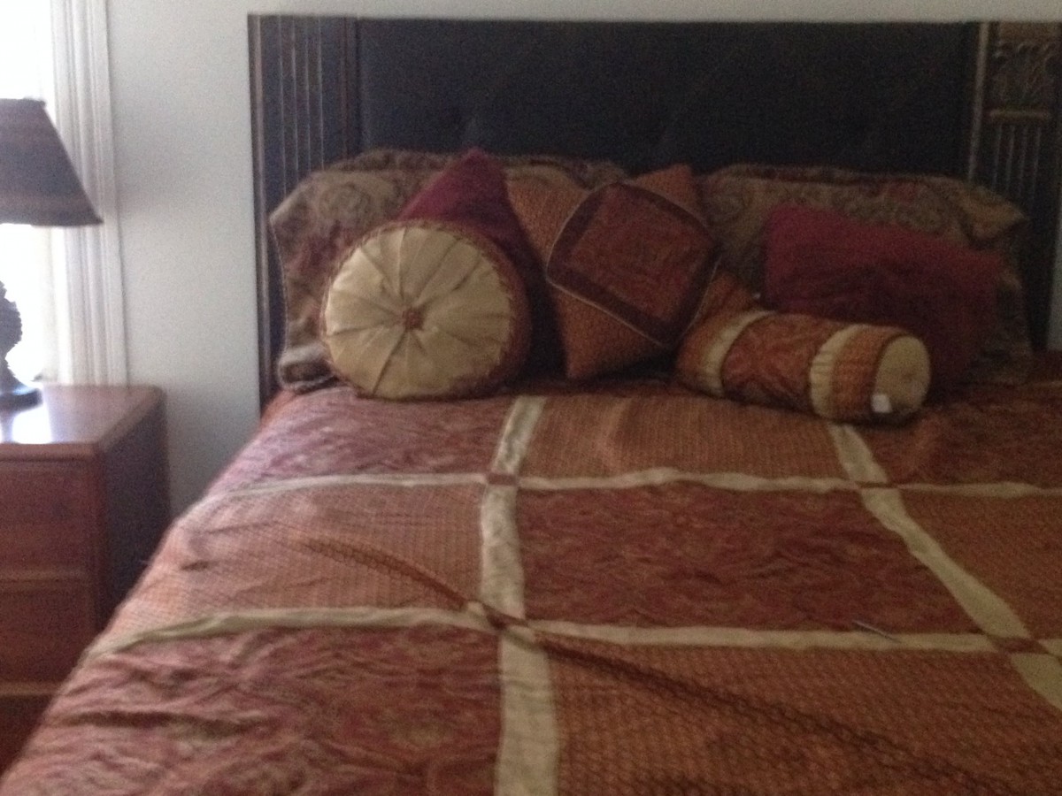 A neatly made bed with decorative pillows and a patterned comforter.