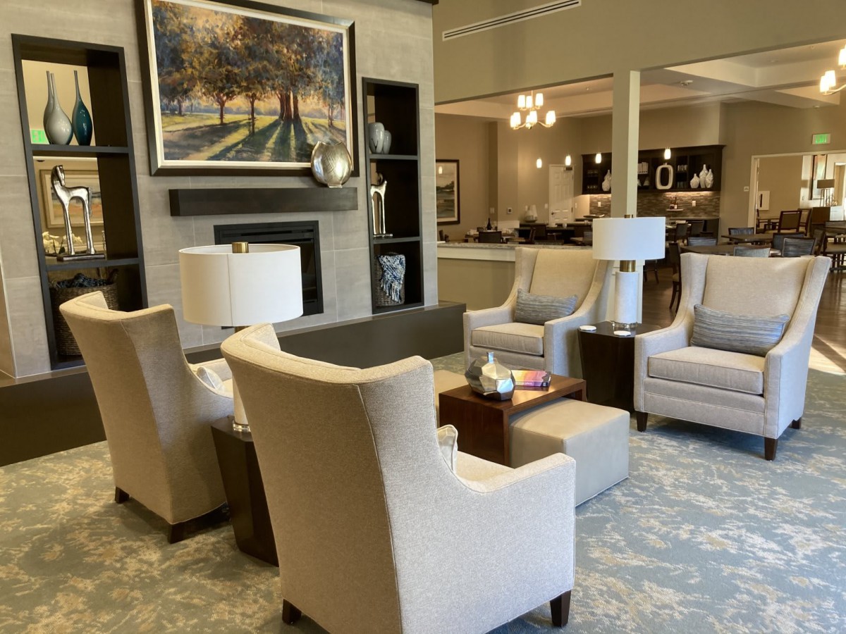 A cozy living room setting with comfortable chairs, a warm lamp, and elegant artwork on the wall.