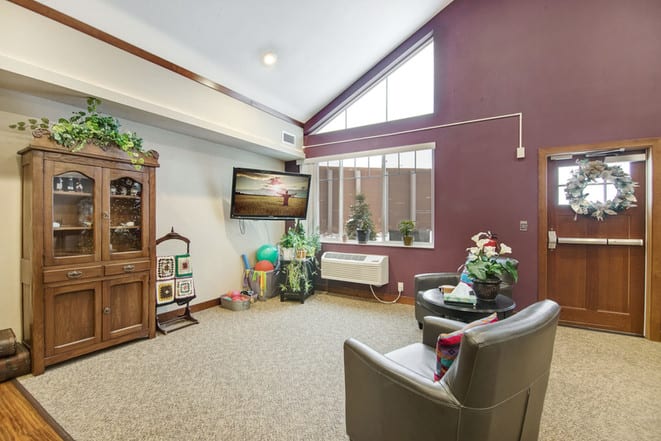 A cozy living room with a television, plants, and comfortable seating.