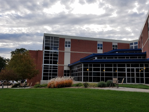 A modern architectural building surrounded by landscaped grass and under a cloudy sky.