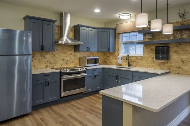A modern kitchen with blue cabinets and stainless steel appliances.