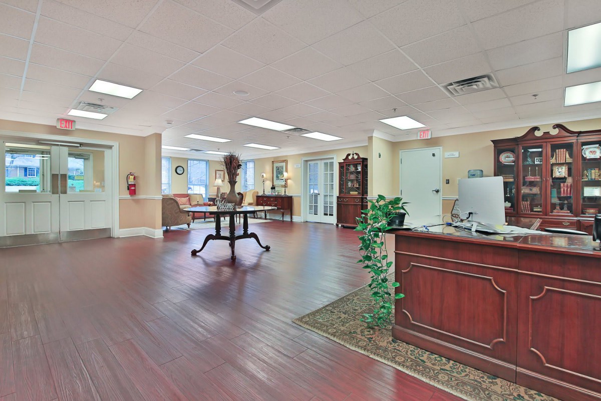 A spacious office lobby with a reception desk and wooden flooring.