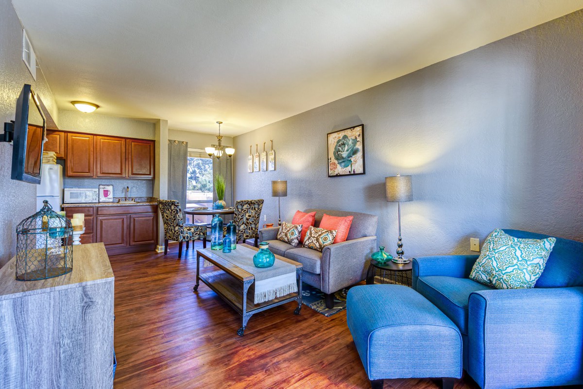 A modern and cozy living room with hardwood floors, featuring a sofa, armchair, coffee table, and stylish decor.