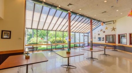A spacious, well-lit cafeteria with large windows and modern furnishings.