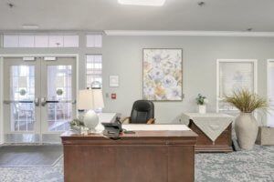 A reception area featuring a desk with a chair, lamp, and decorative artwork on the wall.