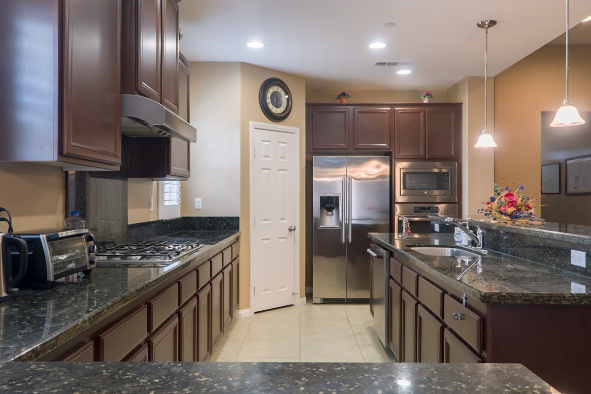 A modern kitchen with dark wood cabinets and stainless steel appliances.