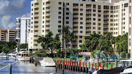 A waterfront apartment building with a marina and boats docked nearby.