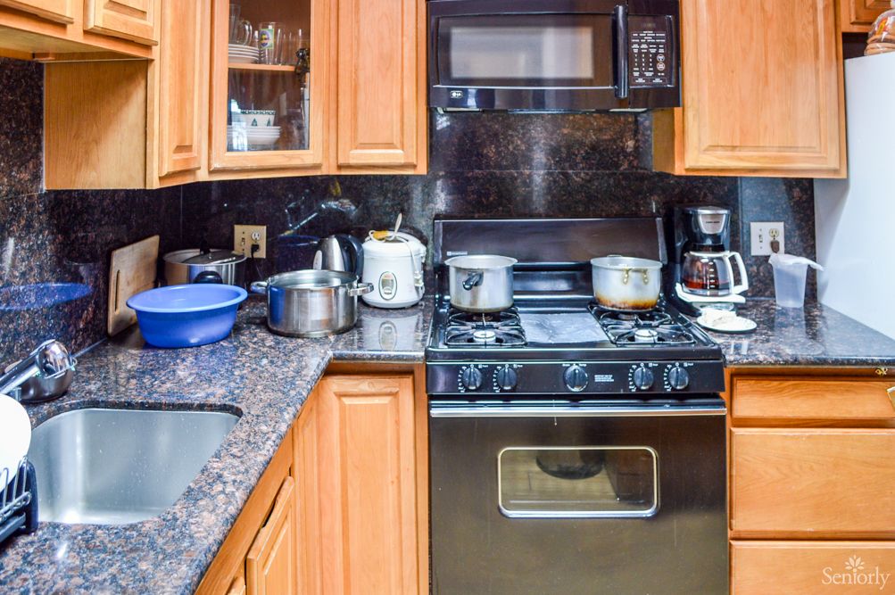 A busy kitchen with various pots and appliances on the stove and countertop.