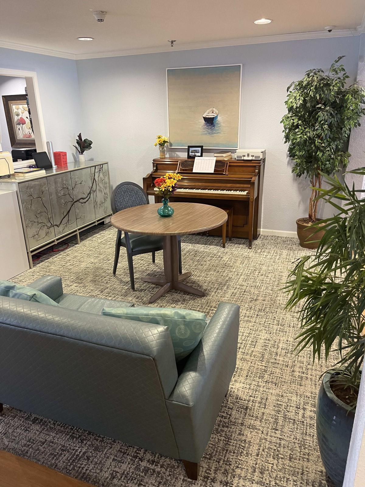 A cozy waiting room with a piano, sofa, and table.