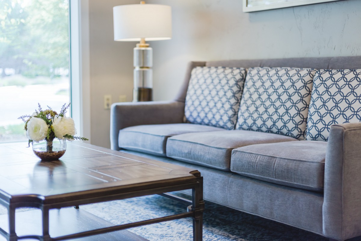 A modern living room with a gray sofa, patterned cushions, and a wooden coffee table.