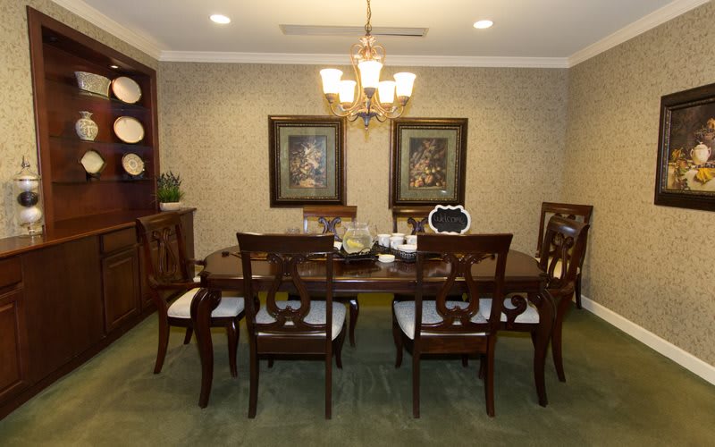 A classic dining room setup with a wooden table and chairs, adorned by a chandelier and wall art.