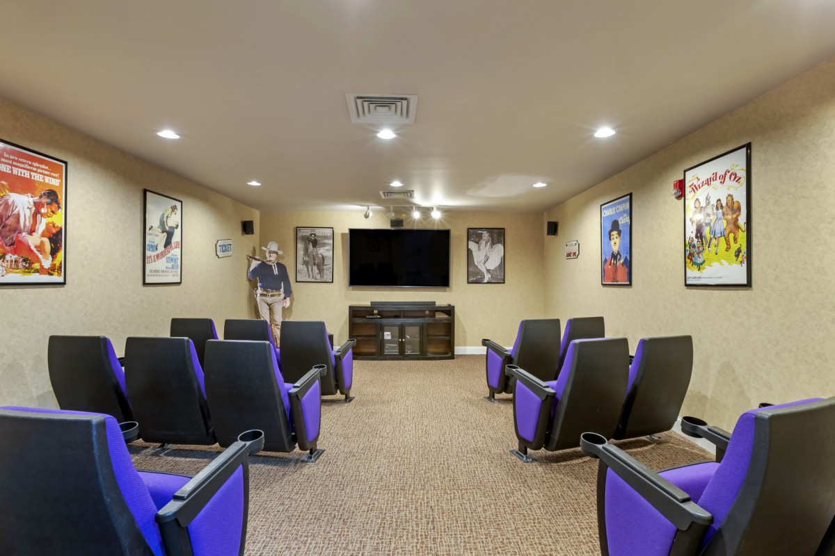 A cozy home theater room with purple seating and a large screen, decorated with classic movie posters.