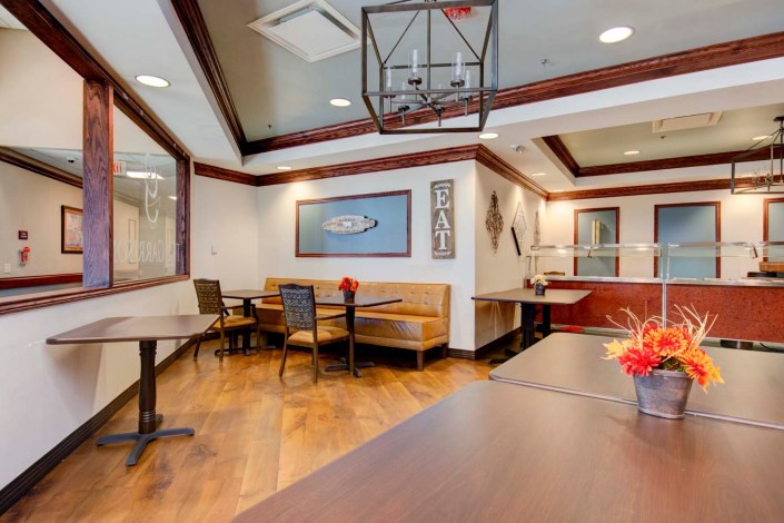 A cozy restaurant interior with tables and booth seating, featuring stylish decor and wooden flooring.