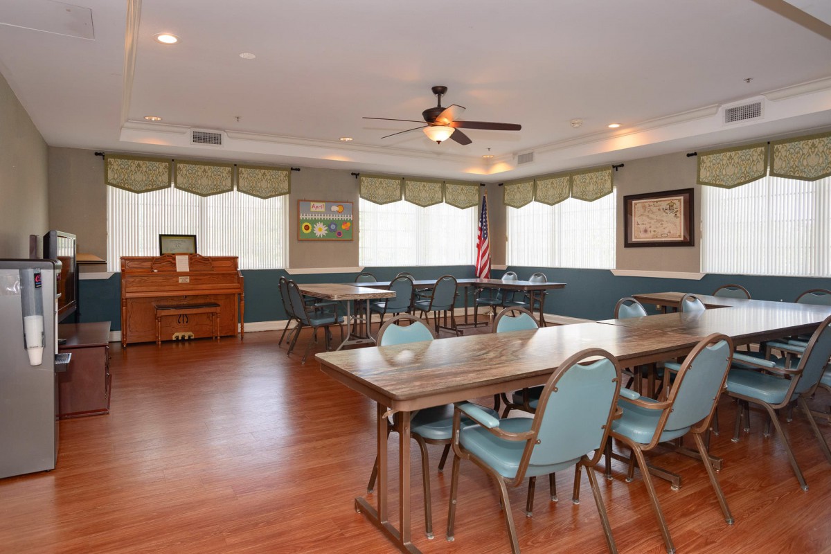A conference room setup with tables and chairs, featuring a piano and an American flag.