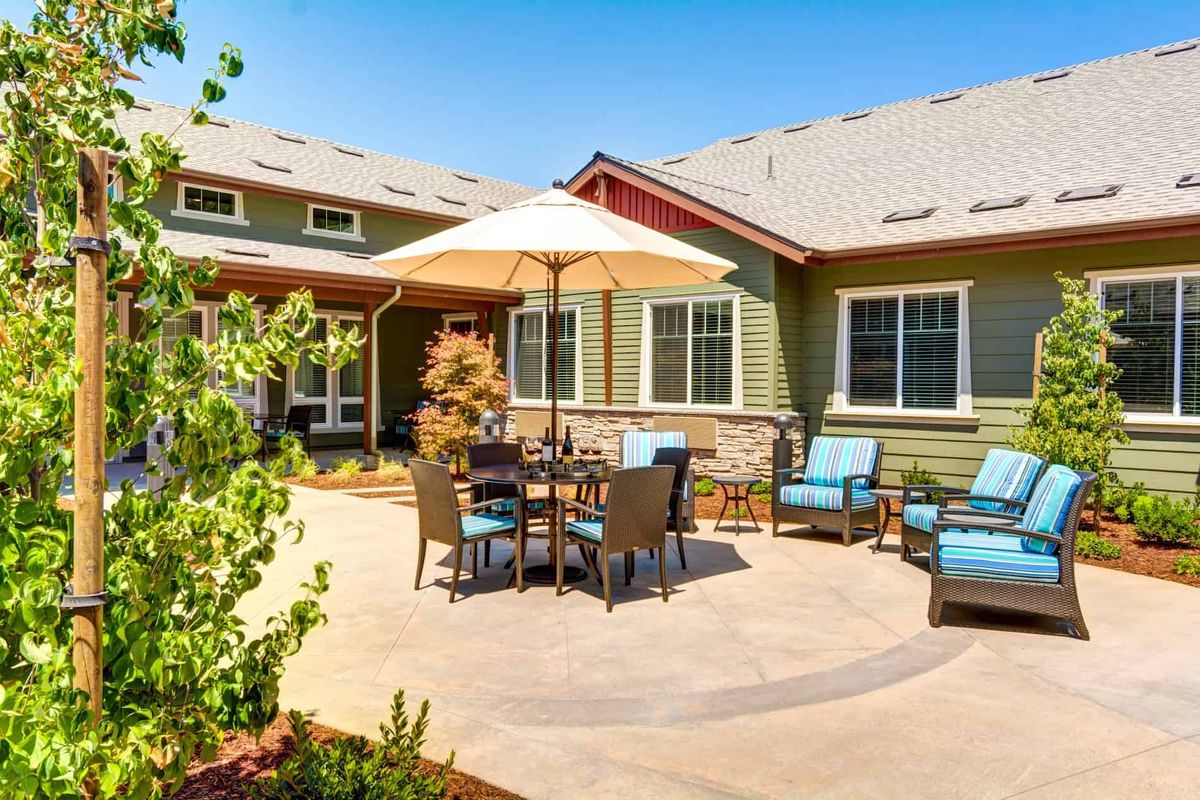 A spacious backyard patio with outdoor furniture and an umbrella on a sunny day.