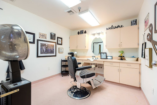 A cozy barber shop interior featuring a styling chair, wooden cabinets, and decor on the walls.