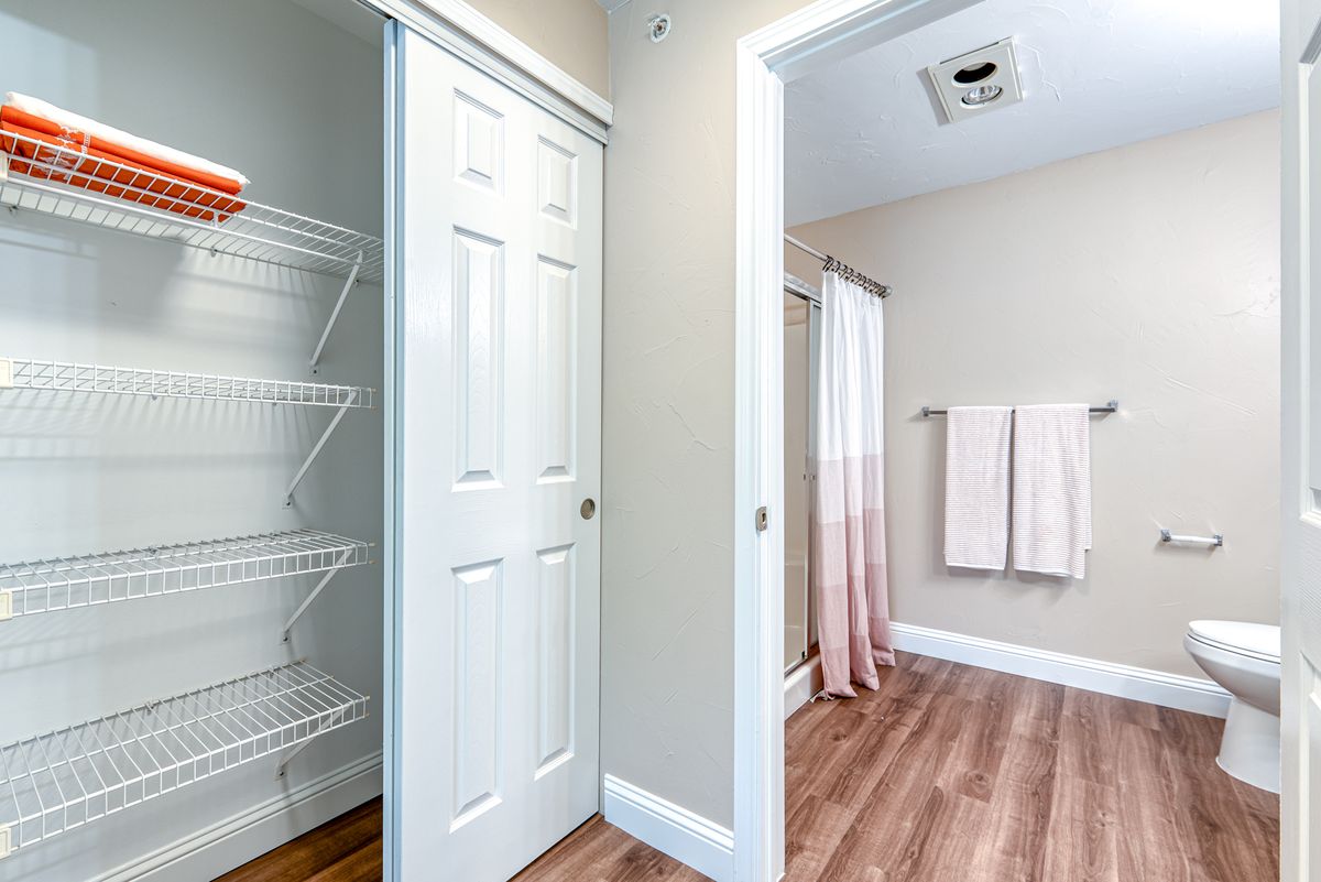 A modern bathroom with a sliding closet door and neatly hung towels.