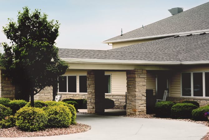 A residential building with stone and siding exterior, surrounded by landscaping.