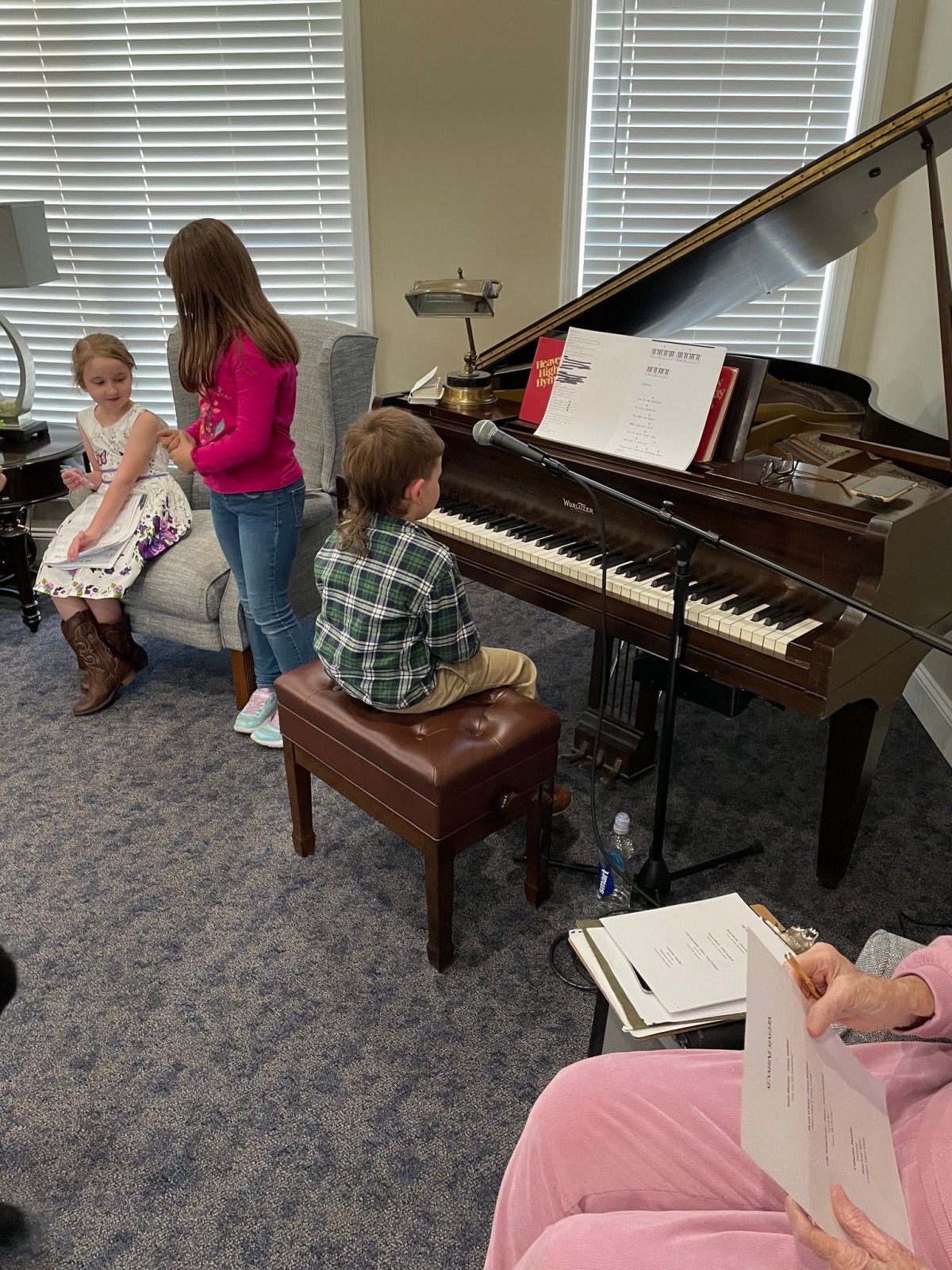 Children participating in a music lesson by the piano.