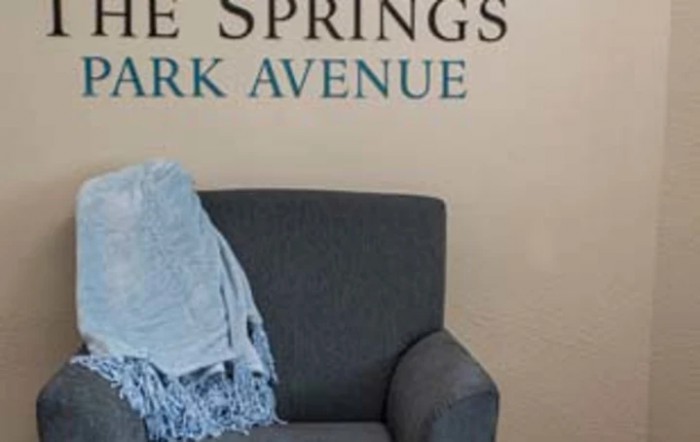 A cozy chair with a blue blanket next to text on the wall.