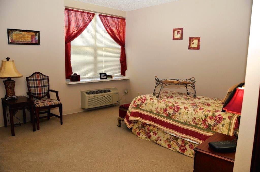 A cozy bedroom with floral decor and red curtains.