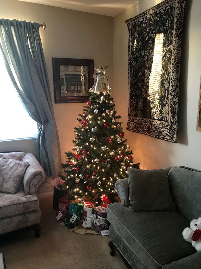 A cozy living room with a beautifully decorated Christmas tree surrounded by gifts.