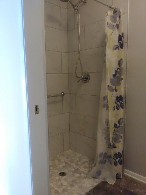 A tiled shower with a floral-patterned curtain in a bathroom.