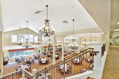 A spacious dining hall with chandeliers and neatly arranged tables viewed from a staircase.