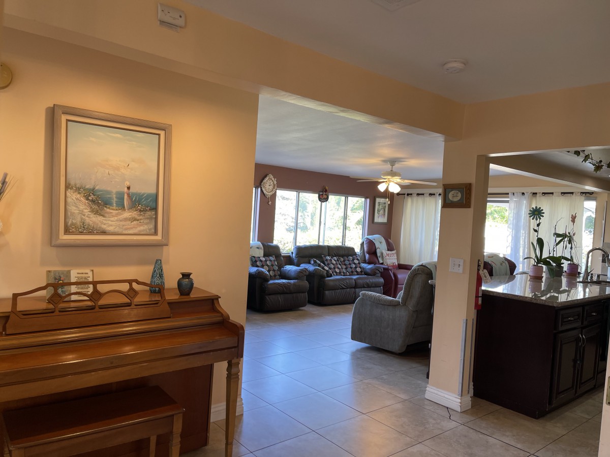 A cozy living room with plush couches, a piano, and large windows allowing natural light in.