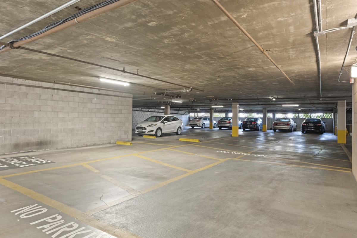 An indoor parking garage with several cars and empty spaces.