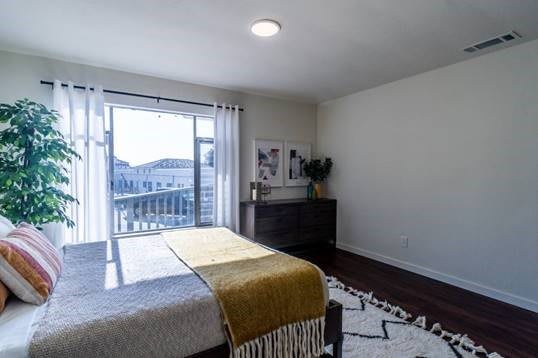 A modern bedroom with minimalist decor and abundant natural light, featuring a balcony view.