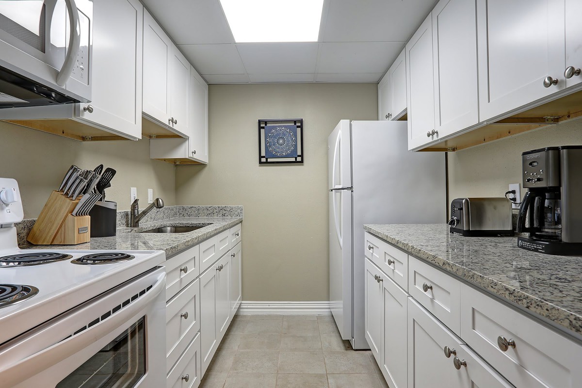 A modern kitchen with white cabinets and appliances.