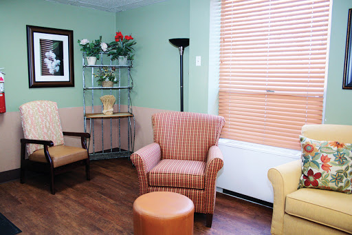 A cozy waiting room featuring comfortable seating, a small table, and decorative plants.