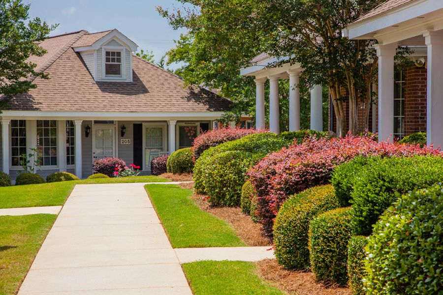 A well-maintained house with a beautifully landscaped garden, featuring manicured bushes and a clear pathway, on a sunny day.