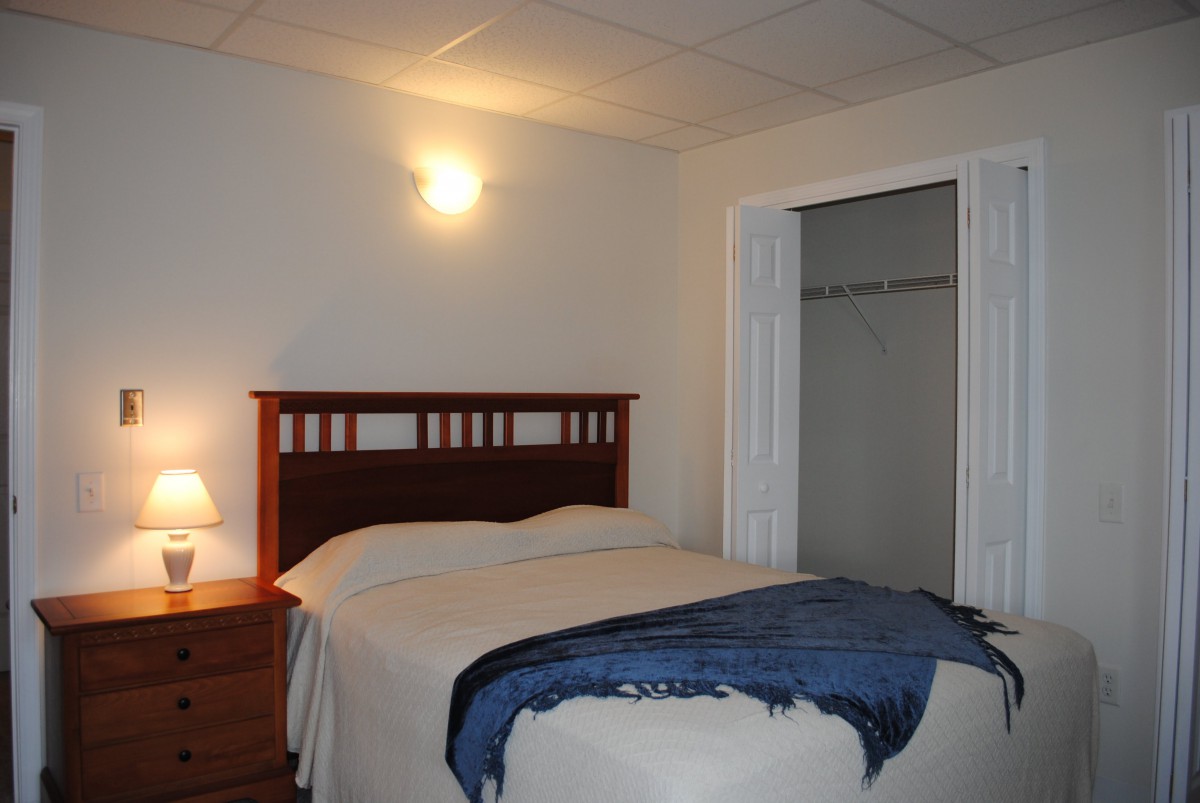 A cozy bedroom with a neatly made bed and a small lamp on the side table.