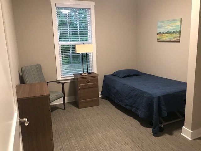 A simple bedroom with a single bed, nightstand, and desk.