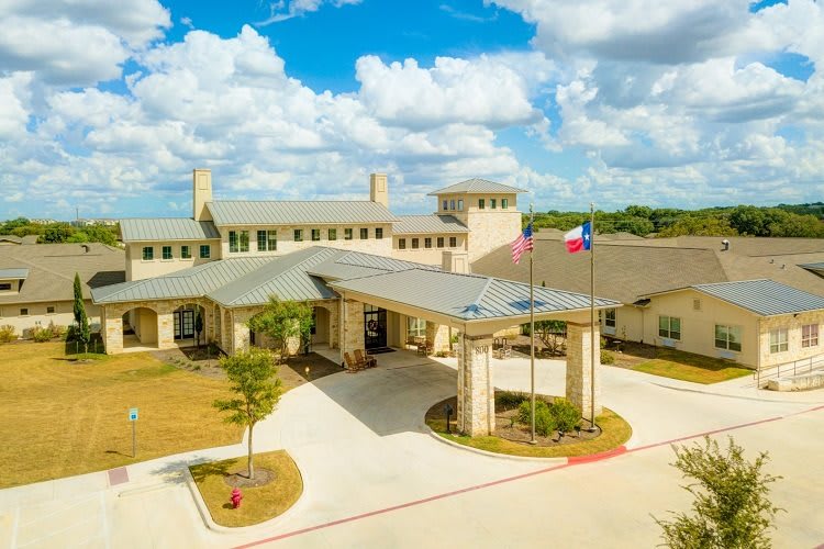 Aerial view of a large building complex with flags and a circular driveway under a partly cloudy sky.