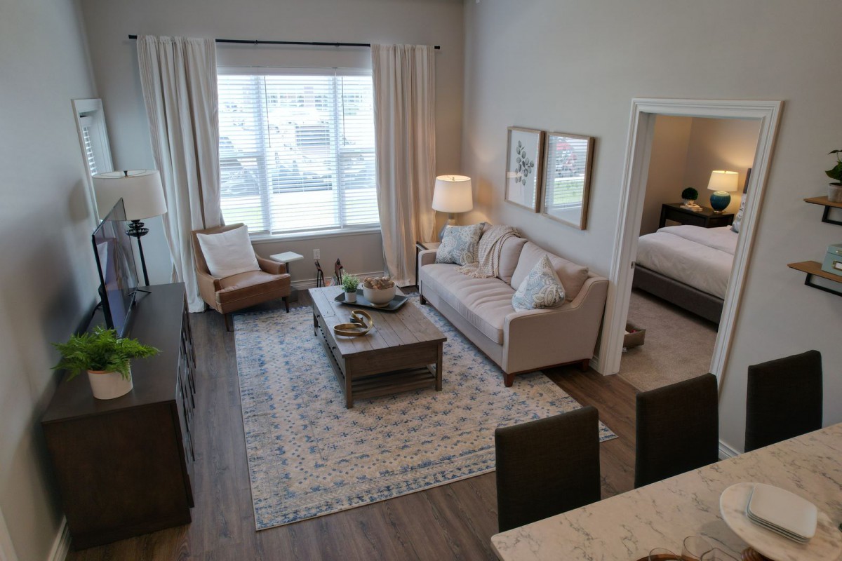 A cozy living room with modern decor, featuring a comfortable sofa, wooden coffee table, and an armchair by the window.