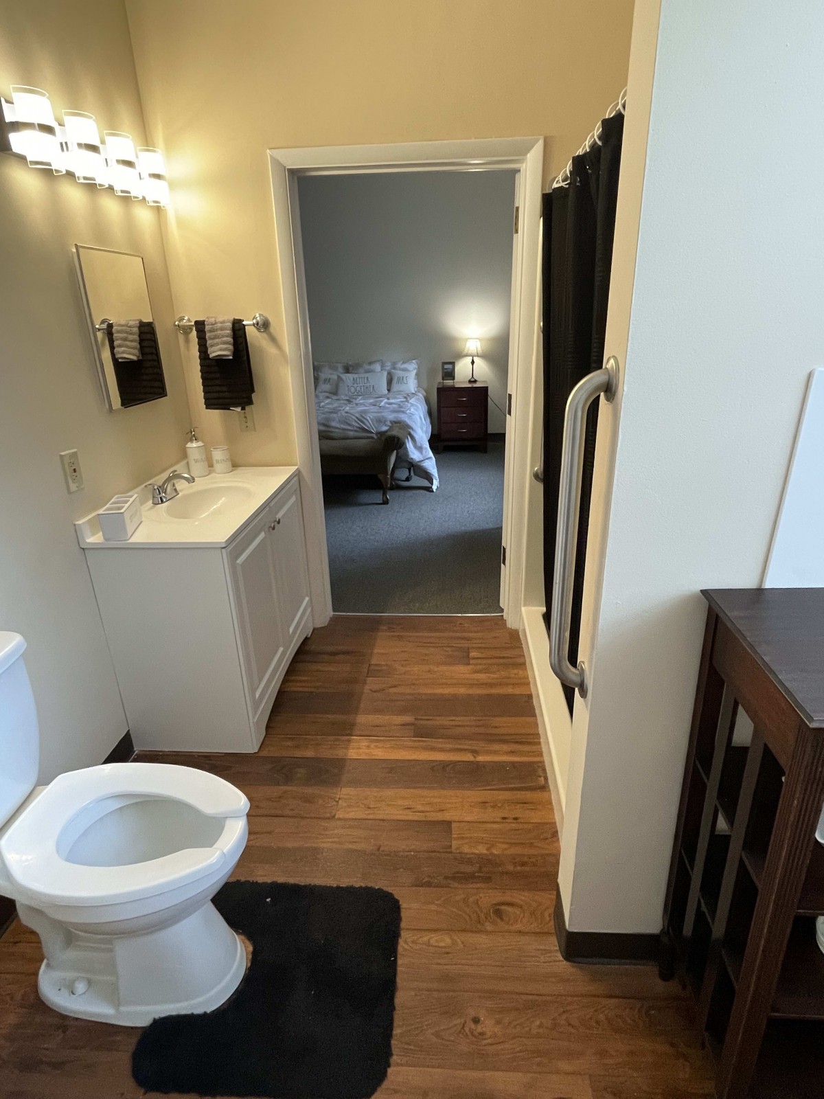 View from a bathroom into an adjacent bedroom with wooden flooring and modern fixtures.